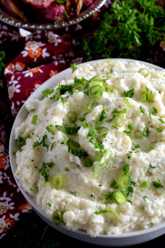 A mashed potato substitute that's health conscious and free of butter and heavy cream. Cheesy Mashed Cauliflower is creamy, flavourful, and delicious without all of the calories and extra fat. The addition of fresh green onions adds a crisp, refreshing taste. #cauliflower #creamcheese #mashedcauliflower #potatoalternative #mashed #thanksgiving #sidedish