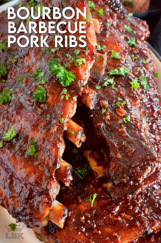 Bourbon Barbecue Pork Ribs are fall-off-the-bone tender. They are slow baked in the oven and basted with a thick and glossy, spicy and sweet, partially homemade bourbon barbecue sauce. Half a rack per person sounds right, yes!? #porkribs #bourbon #barbecue #oven #ribs