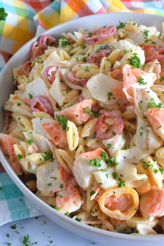 Flaked crab is paired with pasta and peppers in this Crab Pasta Salad. It is tossed in a creamy and tangy dressing made with mayonnaise, old bay seasoning, celery salt, and more. A great make-ahead salad best served slightly chilled with your favourite grilled beef! It's surf and turf - summer style! #crab #pasta #salad #imitation