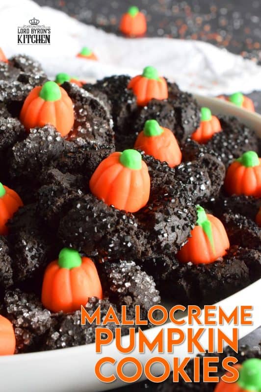 These festive cookies are deliciously decadent. The base is a chocolate cookie that has been darkened to resemble the blackness that goes hand in hand with Halloween. Before baking, the cookie is rolled in black sanding sugar which adds a glistening effect. Finally, a Mellocreme Pumpkin is pushed into the center to make these one of the most adorable Halloween cookies! #halloween #mellocreme #pumpkin #cookies #candy #candycorn