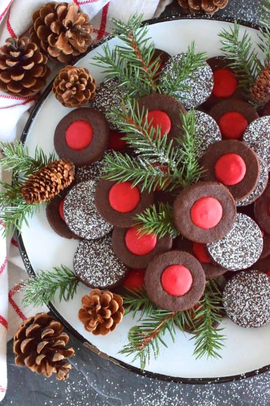 Christmas baking is never complete without a cookie recipe or two that requires one to break out their stash of cookie cutters. In the case of these Chocolate Holly Berry Cookies, it's just a round cookie cutter, but it still feels Christmassy to use any shape! These cookies have a crispy, chocolaty cookie base with a bright red holly berry center - aren't they festive? #christmas #holiday #baking #cookies #chocolate #shortbread #holly