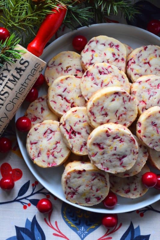 Have you been surprised by unexpected holiday guests in the past? Prepare these cookies in advance and bake them up in a hurry whenever needed. Straight from the fridge to the oven, Orange Cranberry Cookies are delicious and gorgeous! As an added bonus, they will help keep you looking like the baking genius you are! #shortbread #cranberry #orange #zest #cookies #christmas #holiday #baking