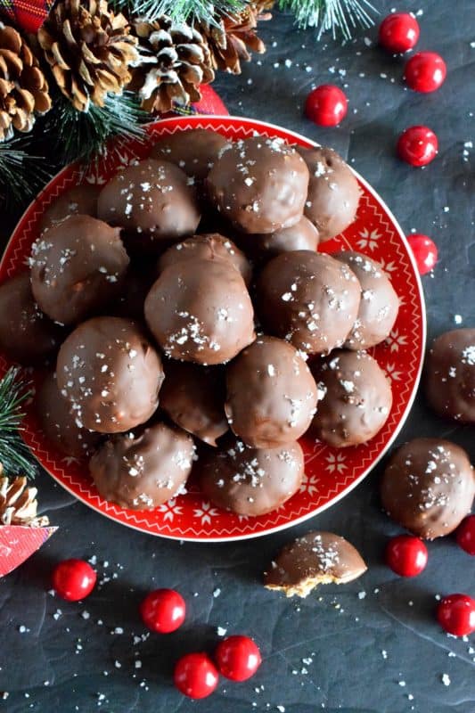 This is a cookie that has been baked into a ball and then dipped into melted chocolate and topped with flaked sea salt. If you love the combination of salty and sweet, than Pretzel Chocolate Cookies are for you! #christmas #holiday #baking #cookie #balls #chocolate #pretzels #cookieexchange