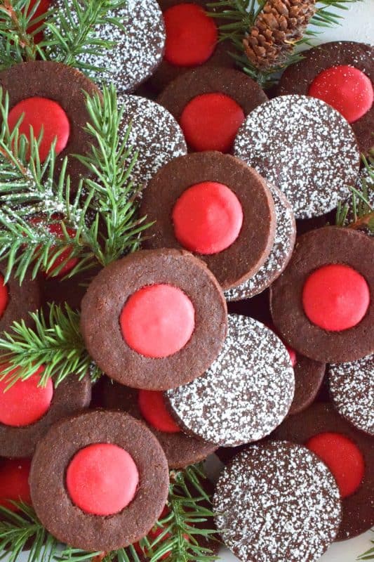 Christmas baking is never complete without a cookie recipe or two that requires one to break out their stash of cookie cutters. In the case of these Chocolate Holly Berry Cookies, it's just a round cookie cutter, but it still feels Christmassy to use any shape! These cookies have a crispy, chocolaty cookie base with a bright red holly berry center - aren't they festive? #christmas #holiday #baking #cookies #chocolate #shortbread #holly