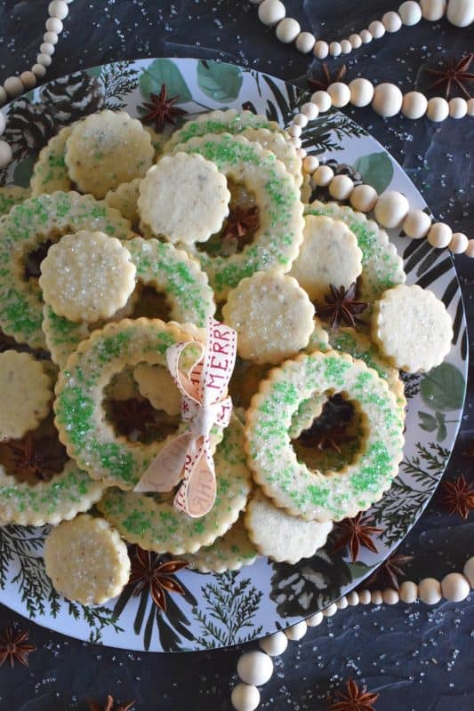 These tender, flaky, yet crisp Anise Wreath Cookies are prepared with a basic rolled cookie dough, but flavoured with crushed anise seeds. Sprinkled with green sanding sugar, these licorice-flavoured cookies are a great addition to any holiday cookie exchange or cookie platter! #christmas #holiday #baking #cookies #wreath #anise