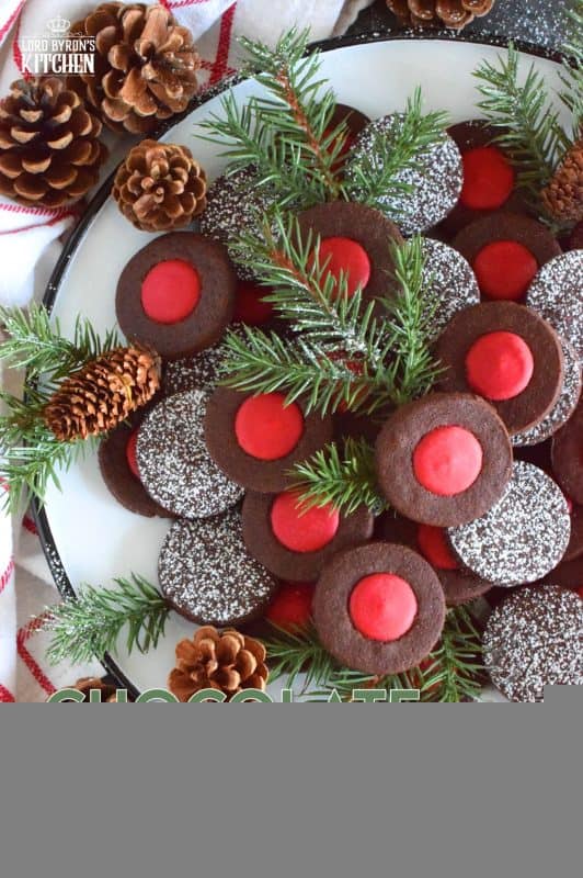 Christmas baking is never complete without a cookie recipe or two that requires one to break out their stash of cookie cutters. In the case of these Chocolate Holly Berry Cookies, it's just a round cookie cutter, but it still feels Christmassy to use any shape! These cookies have a crispy, chocolaty cookie base with a bright red holly berry center - aren't they festive? #christmas #holiday #baking #cookies #chocolate #shortbread #holly