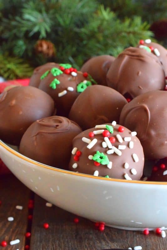 When it comes to truffles that melt in your mouth, Holiday Buttercream Truffles are the best! The bright white centers are prepared with cream cheese and butter, just like the beginnings of a good cake frosting! Dipped in melted milk chocolate, it's hard to eat just one of these! #truffles #buttercream #cookies #nobake #christmas #holiday #chocolate