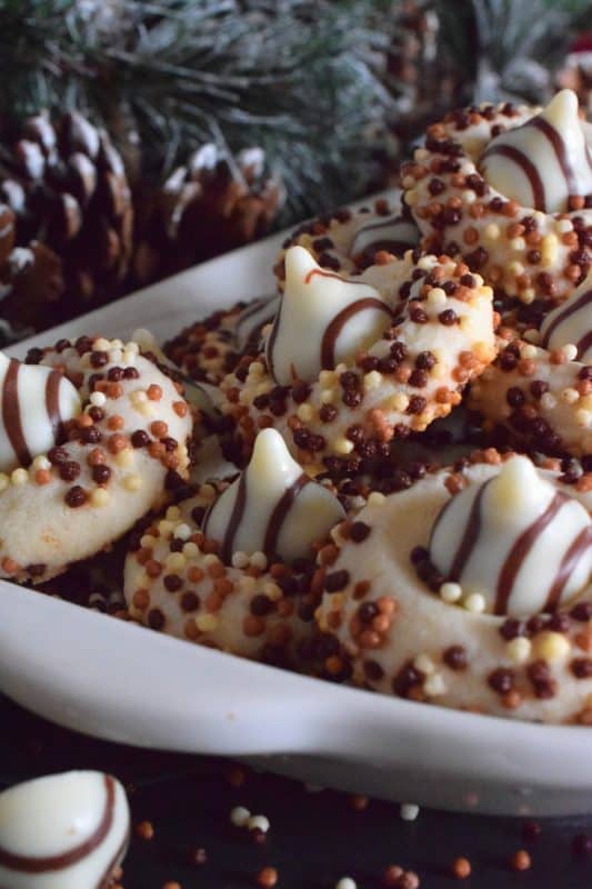 Christmastime is rushed and hurried, especially for the home cook, which leaves little time or desire for cookies that require chilled dough and rolling pins. Hershey Blossom Cookies are made with a whipped shortbread dough, rolled in sprinkles and dotted with a chocolate kiss. They're simple, beautiful, and delicious! Also, they're ready to eat in less than 30 minutes! #hershey #chocolatekiss #kiss #cookies #christmas #holiday #baking