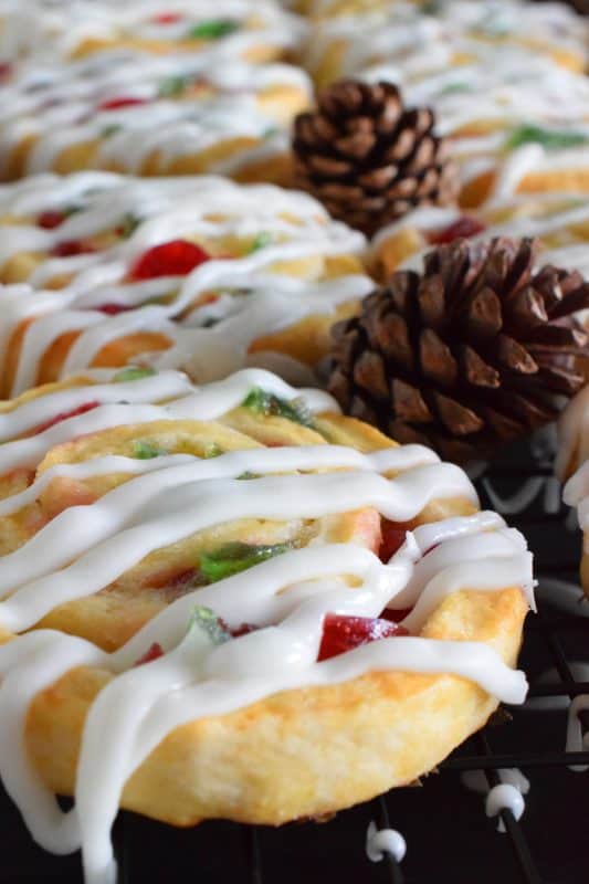 One of my favourite Christmas ingredients is being put to great use today! Cherry Pinwheel Cookies are made with a light, biscuit-like dough and rolled with red and green candied cherries. Drizzled with a basic sweet icing, these are absolutely delicious and very festive too! #christmas #holiday #baking #cherries #candiedcherries #cherry #redandgreen #drizzle