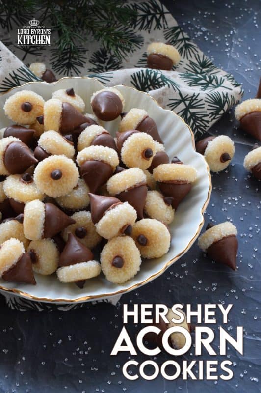 These adorable bite-sized cookies are bound to be a complete hit! They look stunning all on their own, but are perfect for filling in the gaps on your Christmas cookie platter. Hershey Acorn Cookies are prepared with a miniature homemade cookie, and paired with a chocolate kiss and a single chocolate chip! #christmas #holiday #baking #acorn #hershey #kiss #cookies
