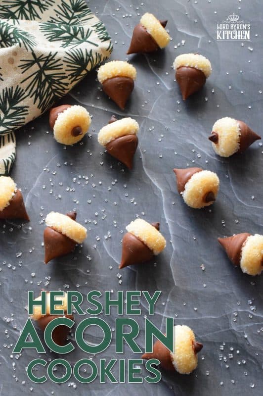 These adorable bite-sized cookies are bound to be a complete hit! They look stunning all on their own, but are perfect for filling in the gaps on your Christmas cookie platter. Hershey Acorn Cookies are prepared with a miniature homemade cookie, and paired with a chocolate kiss and a single chocolate chip! #christmas #holiday #baking #acorn #hershey #kiss #cookies