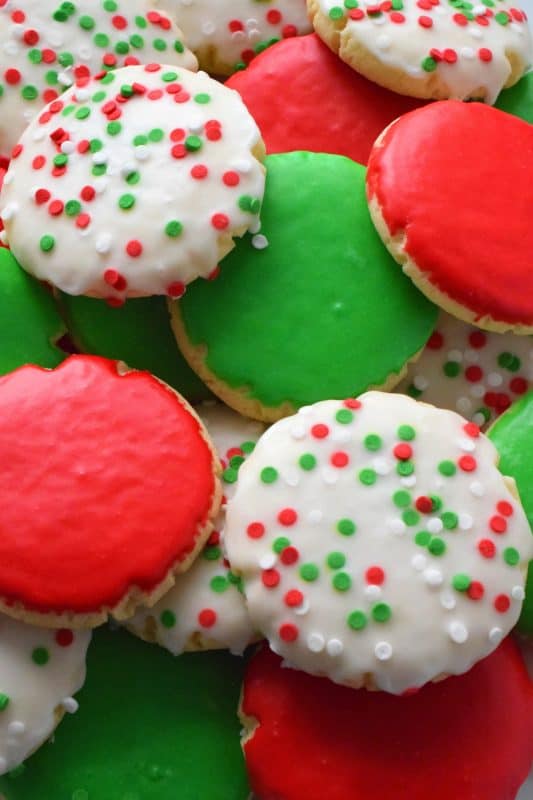 This recipe consists of a melt-in-your-mouth sugar cookie base, topped with a thin, sugary glaze, and festive sprinkles. Holiday Sugar Cookies are brightly and vividly coloured with red and green frosting and will appeal to both the little kids and the big kids in your life! #christmas #holiday #baking #sugarcookies #cookies