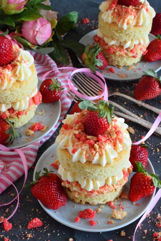 These gorgeous mini individual-sized cakes are super easy to make and look quite impressive. Stacked Vanilla Strawberry Shortcakes are prepared with vanilla sheet cake, strawberry shortcake crumbs, buttercream frosting, and fresh strawberries. You're going to love these shortcakes! #strawberry #strawberryshortcake #cake #stackedcake #layeredcake #valentines