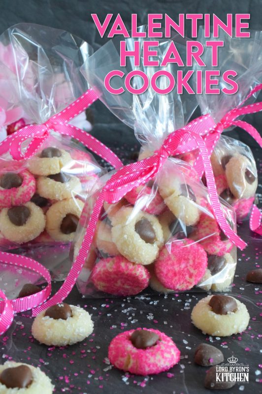 These adorable bite-sized cookies are bound to be a complete hit! They look stunning all on their own, but are perfect for gift giving to your favourite valentine! Valentine Heart Cookies are prepared with a basic butter and sugar cookie, rolled in pink sugar, and topped with a chocolate heart! #valentine #cookies #pinkrecipes #valentinerecipes