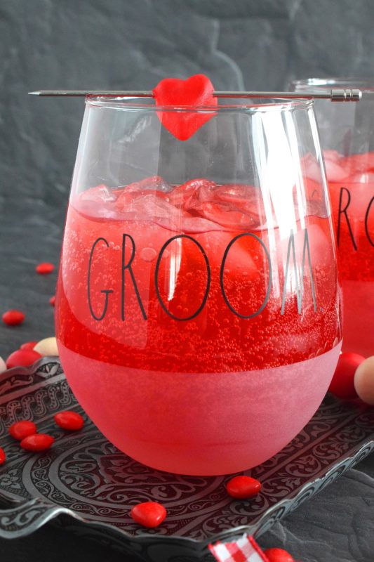 This slightly spicy cocktail is vibrantly red and perfect to share with that special someone on Valentine's Day! Prepared with a homemade, easy-to-make simple syrup made with candy hearts, a good splash of vodka, and club soda, this cocktail is bubbly and has a cozy, warm flavour! #valentines #cocktail #cinnamonhearts #redhots #valentinesday