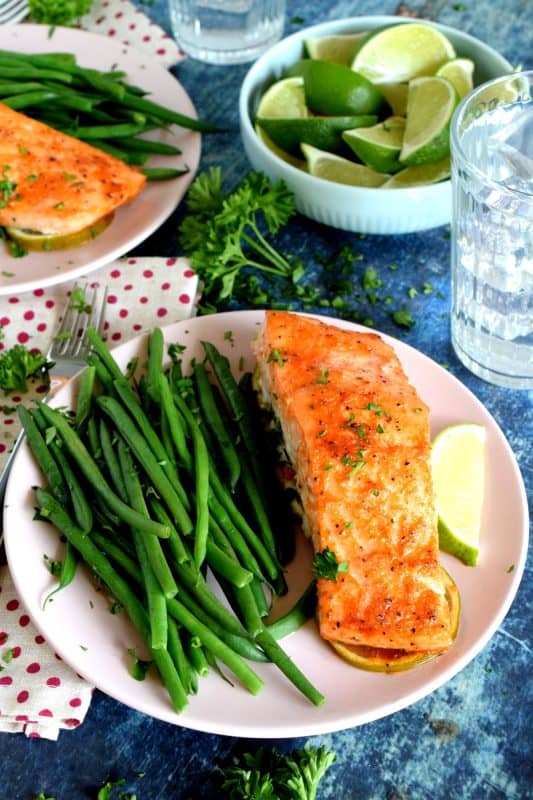 Slightly sweet with a little tartness, Sriracha Honey Lime Salmon is oven baked on a bed of sliced limes for extra zing and fresh flavour. The sriracha and honey combine to make a wonderful basting sauce with the perfect balance of sweet and heat. #sriracha #honey #honeylime #salmon #bakedsalmon #spicysalmon