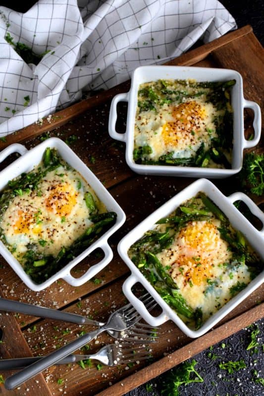 Simple, hearty, and delicious; individual portions make these Baked Asparagus with Eggs and Parmesan easy to serve and a little elegant too! This is exactly how I serve asparagus as a main! Dip some crusty bread in the soft yolks - it's scrumptious!! #baked #asparagus #egg #parmesan #brunch