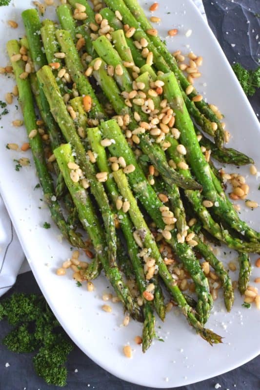 This side dish is great any time, but is best when fresh asparagus is in season. Roasted Asparagus with Pine Nuts and Parmesan has perfectly cooked asparagus with the saltiness of freshly grated parmesan and the nuttiness of delicately toasted pine nuts. Super fast, super yummy, and super easy! #asparagus #pinenuts #parmesan #roasted #sidedish