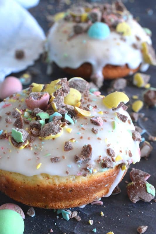 When it comes to donuts, chocolate is always a great choice. Easter Mini Egg Donuts are prepared with a vanilla batter, loaded with crushed Cadbury mini eggs, topped with a simple sugar glaze, and more crushed mini eggs! Easter treats never tasted so good! #donuts #bakeddonuts #doughnuts #easter #cadbury #minieggs