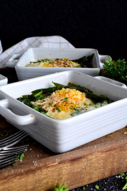 Simple, hearty, and delicious; individual portions make these Baked Asparagus with Eggs and Parmesan easy to serve and a little elegant too! This is exactly how I serve asparagus as a main! Dip some crusty bread in the soft yolks - it's scrumptious!! #baked #asparagus #egg #parmesan #brunch