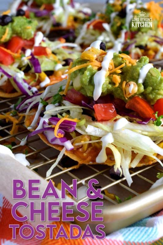 Bean and Cheese Tostadas are piled high with fresh veggies and topped with guacamole and sour cream. They're like an unrolled burrito with the crunch of a taco. Try eating just one! #tostadas #Mexican #recipes #vegetarian