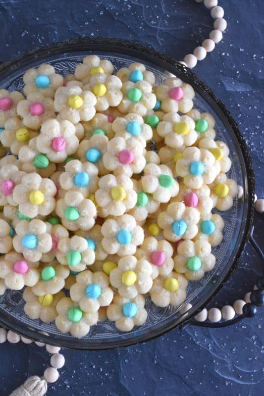 A good spritz cookie should taste slightly sweet and buttery. The cookie should be slightly crumbly, but not dry, and it should feel like it’s melting in your mouth. Topped with a single candy-coated chocolate, these Springtime Flower Cookies are not only delicious but pretty and cheerful too! #spritz #cookies #easter #spring #flower #cadbury #minieggs