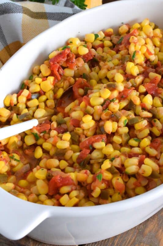 This warm and creamy corn salad is prepared with old bay seasoning, fried onions, bell peppers, garlic, and tomatoes. It's a perfect side dish for a backyard barbecue or a weeknight cold weather dinner. Serve with your favourite mains or spoon it onto grilled burgers and hot dogs. This side is versatile and delicious! #salad #corn #oldbay #creamedcorn #sidedish #vegetarian