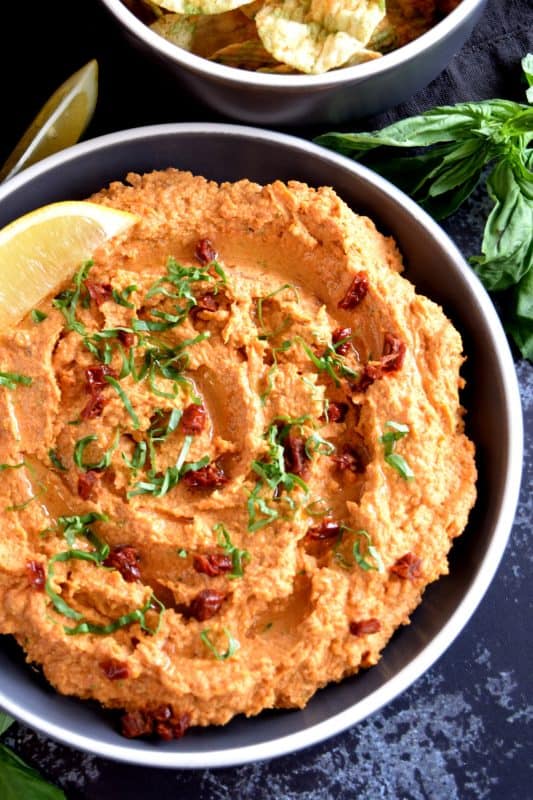 Homemade hummus is always best and it's easy too! All you need is a few basic ingredients to make this delicious Sun Dried Tomato and Fresh Basil Hummus. This one is savoury and slightly salty. And, the brightness from the fresh lemon juice is stellar! You'll never buy prepared hummus again! #hummus #dip #sundriedtomato #basil