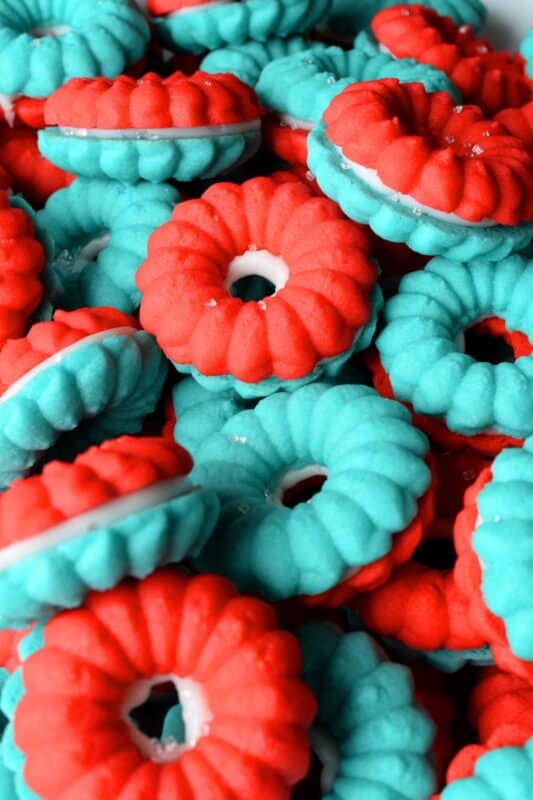 Everyone loves a spritz cookie, especially at Christmas! But, why should they only make an appearance once a year? In this version, I've coloured the cookie dough red and blue and sandwiched them with white frosting. These are most certainly bright and festive - perfect for your 4th of July celebrations! #spritz #cookies #sandwichcookies #redwhiteblue #4thofjuly #redwhiteandblue