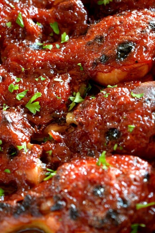 In this Charred Chipotle Chicken recipe, inexpensive drumsticks are baked with onion and then topped with a thick, sweet sauce consisting of chipotle peppers in adobo sauce, vinegar, brown sugar, and more. This is certainly an easily family pleasing main! #bakedchicken #drumsticks #spicychicken #chipotle #adobosauce #saucy