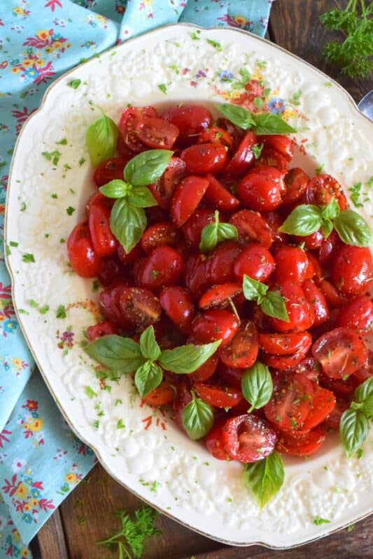 Cherry tomatoes are halved and marinated in a sweet and savoury blend of olive oil, vinegar, honey, and Italian seasoning. Topped with fresh basil leaves, these Marinated Italian Tomatoes make a delicious side dish, salad, or a topping for grilled baguette. #tomatoes #summerfresh #locallygrown #sides #marinated #salad #italian