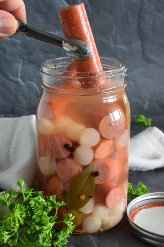 The easy to do recipe combines the flavour of the classic highway gas station pickled wieners with the bright, tart and sweet flavour of jarred pickled onions. Keep a jar in your fridge at all times for a quick snack or an easy lunch served with cheese and crackers! #pickled #wieners #cocktail #onions #pickledwieners