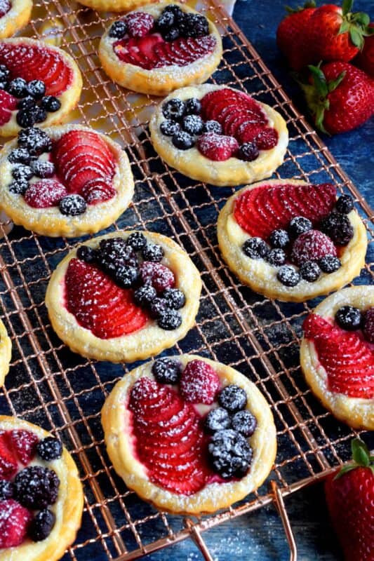 Transform store-bought, frozen sheets of puff pastry into these delightful little tarts filled with fresh berries and a lemony cream cheese filling! Use your favourite berries or fruit and then try to eat just one - it's nearly an impossible feat! #puffpastry #berries #4thofjuly #recipes #summer #creamcheese #tarts #tartlets #fruit