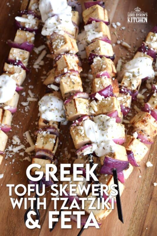 Extra firm tofu is marinated with red onion in a mixture of olive oil and the best quick and easy homemade Greek seasoning.  Grilled until slightly charred and topped with tzatziki and crumbled feta, these skewers are a great grilled meat alternative! #grilledtofu #tofu #greekrecipes #vegetarian #summergrilling