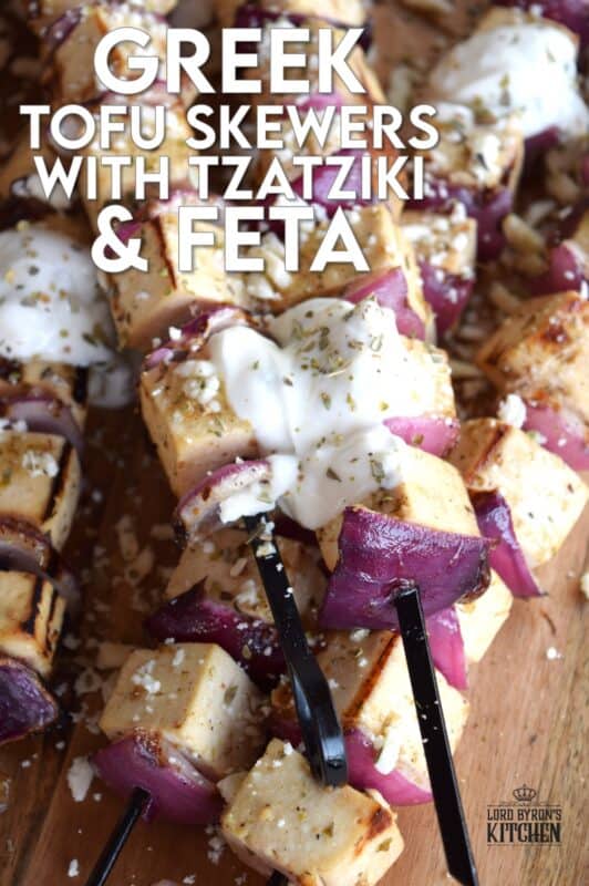 Extra firm tofu is marinated with red onion in a mixture of olive oil and the best quick and easy homemade Greek seasoning.  Grilled until slightly charred and topped with tzatziki and crumbled feta, these skewers are a great grilled meat alternative! #grilledtofu #tofu #greekrecipes #vegetarian #summergrilling