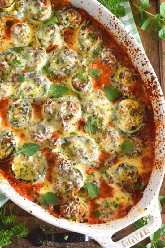 A little lighter on the carbs, Zucchini Lasagna Rolls are prepared by rolling thinly sliced zucchini with spinach, egg, three cheeses, and seasonings. Baked in marinara sauce, don't be fooled by this healthier dish; it is both filling and robust! #zucchini #zucchinirolls #lasagna #lasagnarolls #zucchinilasagna #lowcarb