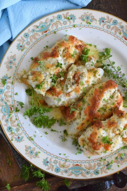 Fresh cod fillets are generously topped with fresh minced garlic and a variety of chopped fresh herbs which is combined with mayonnaise and grated parmesan cheese. The fish is perfectly baked until brown and bubbly. Garlic Herb Baked Cod Fish is both savoury and delicious! #cod #fish #seafood #bakedcod #parmesancod #freshherbs