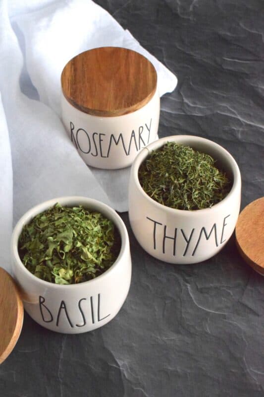 For the past few summers, I have grown a variety of fresh herbs in containers on our back deck. Just before the first frost, they are all harvested and dried indoors for use throughout the winter months. It takes minimal effort, but the reward is huge because the herbs taste better than any store-bought jars you can find! #herbs #drying #indoors #freshherbs #driedherbs