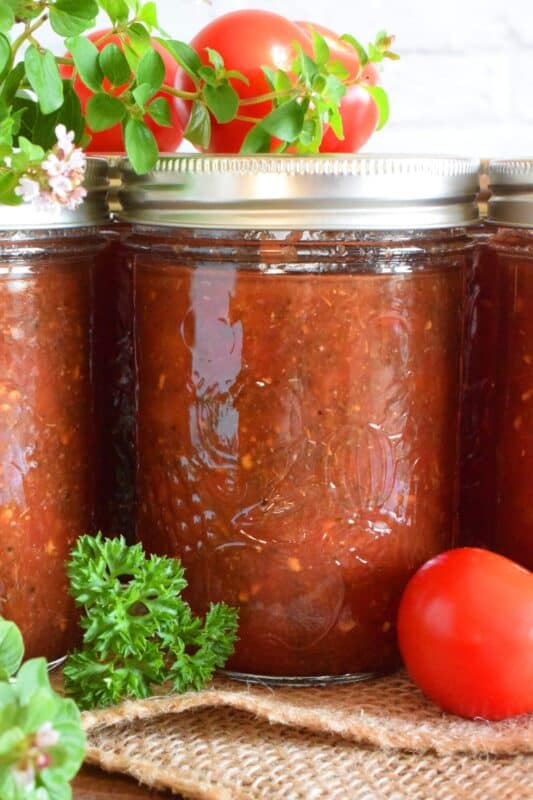 Canned Seasoned Tomato Sauce is prepared with summer fresh, locally grown tomatoes, and seasoned with classic tomato sauce ingredients like onion, garlic, basil, and oregano. Not only will you contain all of that fresh tomato flavour, but you'll cut dinner time prep in half! #tomatosauce #tomatoes #canning #preserves #seasonedsauce #tomato