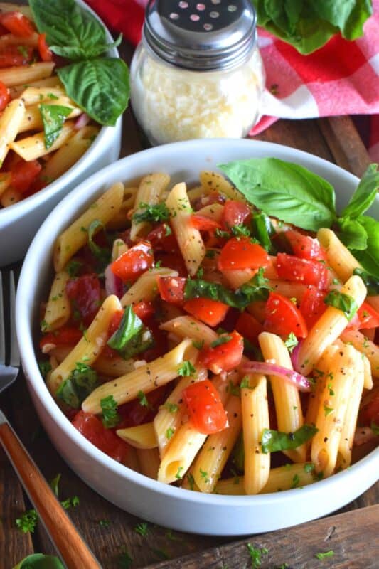This is the ultimate summer pasta salad! Fresh tomatoes are marinated with olive oil, garlic, red onions, and balsamic vinegar before being tossed with cooked pasta and fresh basil. A terrific way to use your best summer fresh tomatoes! #pasta #summerpasta #bruschetta #pastasalad #tomatoes #summertomatoes #tomatorecipes