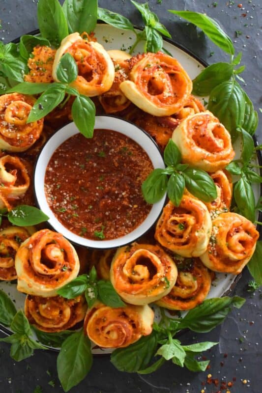 Whip up a batch of these Cheesy Pizza Roll Dippers quickly and easily with the help of store-bought, frozen pizza dough! Layer the dippers with lots of cheese, a quick and easy homemade pizza sauce, and toppings of your choice! These puff up in the oven and are brown and slightly crispy on the bottom with ooey-gooey cheese bubbling out of the top. Complete with a delicious marinara dip, who could resist? #pizza #pizzarolls #rollups #dip #dippers