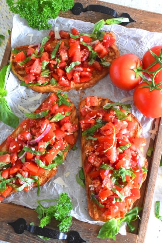 Summer fresh tomatoes are marinated with olive oil, garlic, red onions, and balsamic vinegar and piled high on garlic-rubbed grilled toast. Marinated Tomato Toasts are one of my favourite ways to use up my home-grown tomato harvest! #tomato #tomatoes #summerfresh #toasts #sourdough #bread #marinated