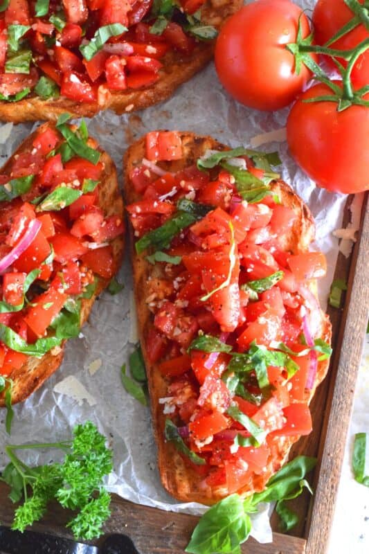 Summer fresh tomatoes are marinated with olive oil, garlic, red onions, and balsamic vinegar and piled high on garlic-rubbed grilled toast. Marinated Tomato Toasts are one of my favourite ways to use up my home-grown tomato harvest! #tomato #tomatoes #summerfresh #toasts #sourdough #bread #marinated