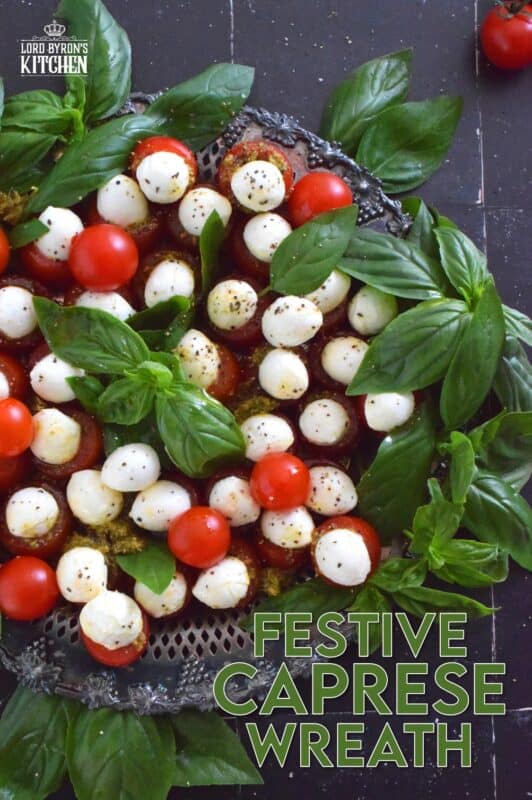 Simple, sweet, and cheesy!? You bet! This gorgeous Festive Caprese Wreath is easily prepared with hollowed-out cherry tomatoes stuffed with basil pesto and mini bocconcini. Sprinkle over some freshly ground black pepper, drizzle with olive oil, and tuck in some fresh basil leaves before serving! #festive #caprese #ediblewreath #tomatoes #bocconcini