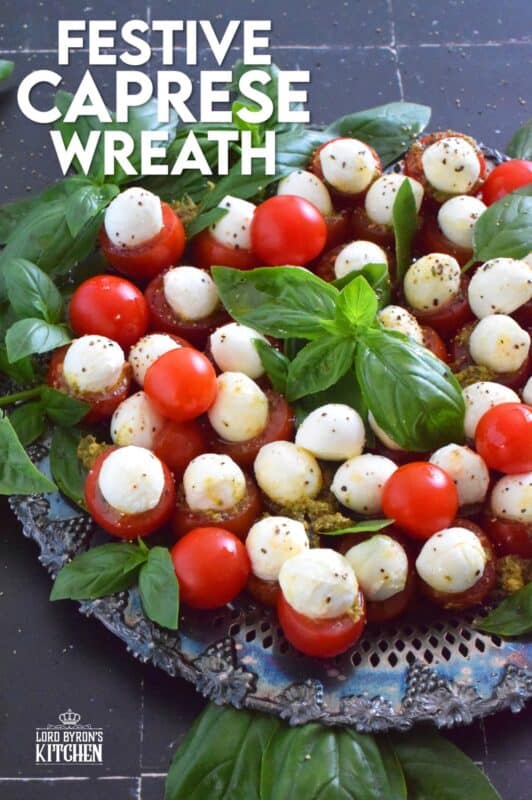 Simple, sweet, and cheesy!? You bet! This gorgeous Festive Caprese Wreath is easily prepared with hollowed-out cherry tomatoes stuffed with basil pesto and mini bocconcini. Sprinkle over some freshly ground black pepper, drizzle with olive oil, and tuck in some fresh basil leaves before serving! #festive #caprese #ediblewreath #tomatoes #bocconcini