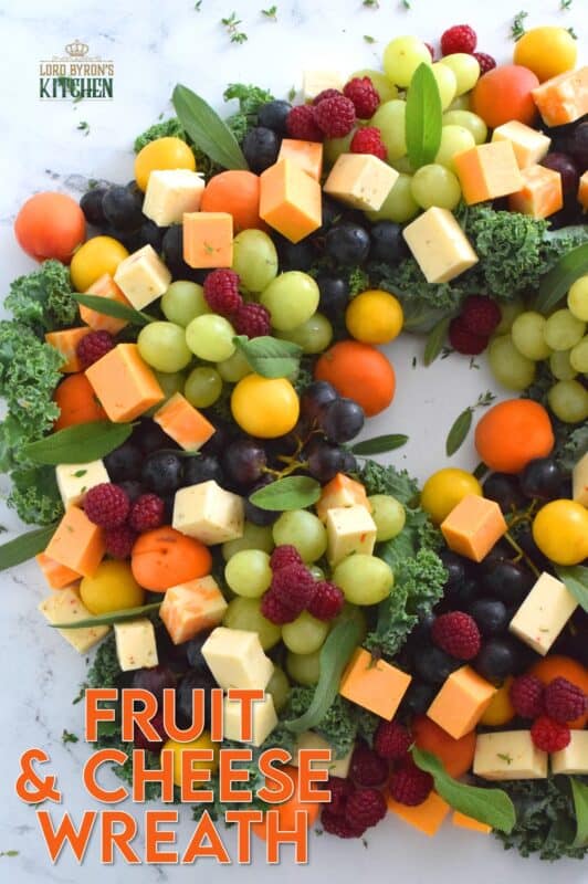 An edible wreath consisting of red and green grapes, fresh apricots, tart plums, vibrantly red raspberries, and various types of cheese, this beautifully festive Fruit and Cheese Wreath is a wonderful way to display and serve your guests this holiday season! #christmas #holiday #fingerfoods #appetizers #cheeseplatter #charcuterie #grazing #board