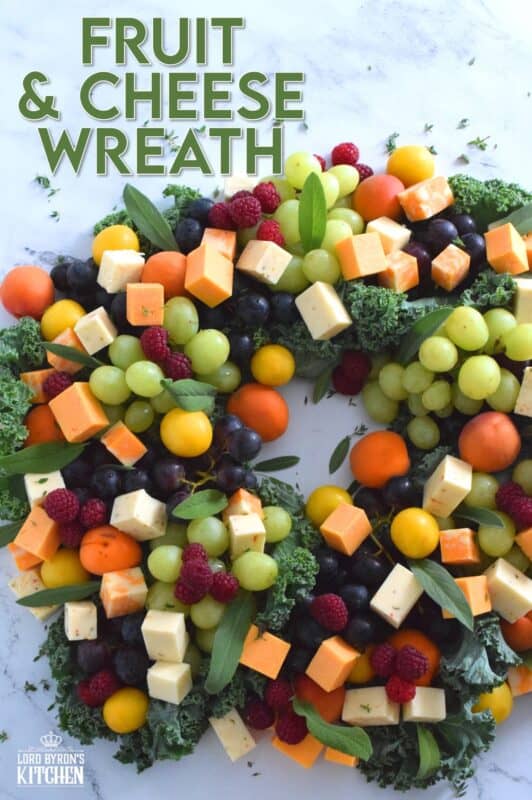 An edible wreath consisting of red and green grapes, fresh apricots, tart plums, vibrantly red raspberries, and various types of cheese, this beautifully festive Fruit and Cheese Wreath is a wonderful way to display and serve your guests this holiday season! #christmas #holiday #fingerfoods #appetizers #cheeseplatter #charcuterie #grazing #board