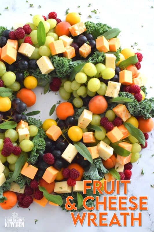 An edible wreath consisting of red and green grapes, fresh apricots, tart plums, vibrantly red raspberries, and various types of cheese, this beautifully festive Fruit and Cheese Wreath is a wonderful way to display and serve your guests this holiday season! #christmas #holiday #fingerfoods #appetizers #cheeseplatter #charcuterie #grazing #board