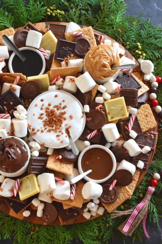 The ultimate rich and indulgent treat can be summed up in three words - S'mores Dessert Wreath! Assemble all of the ingredients into a large wreath and set it out for your guests. Utilizing marshmallow fluff will mimic the gooey marshmallow effect everyone craves, but you can make s'mores more authentic by roasting the marshmallows using your fireplace or even a candle! #smores #christmas #holiday #dessertbar