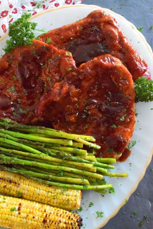 The combination of a sweet and smoky barbecue sauce with jarred peach preserves is the perfect addition to accompany these oven-baked ham steaks. Add some garlic, onion, and a little ground black pepper to round out the flavours and you've got a very delicious family-style recipe for tonight's dinner! #ham #hamsteak #peach #bbq #bakedham